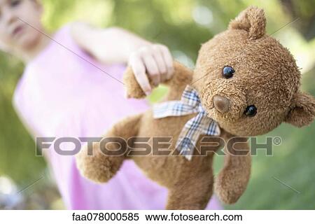 Stock Photography - Girl holding teddy bear, low angle view. Fotosearch