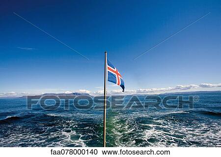 Stock Image - Icelandic flag with sea in background. Fotosearch