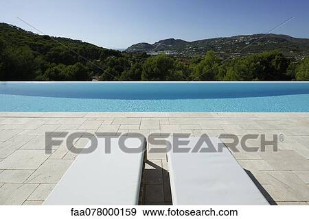 Stock Photo - Lounge chairs beside swimming pool. Fotosearch