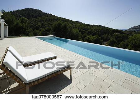 Stock Photo - Lounge chairs beside swimming pool. Fotosearch