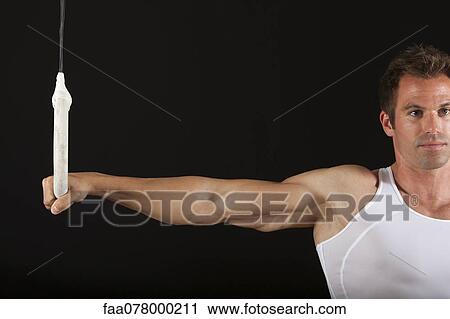 Stock Image - Male gymnast holding onto gymnastics ring. Fotosearch
