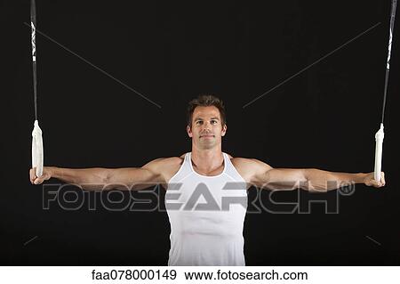 Stock Photo - Male gymnast holding onto gymnastics rings. Fotosearch