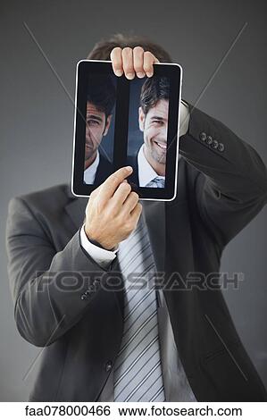 Stock Photograph - Man hiding behind images of himself frowning and smiling. Fotosearch