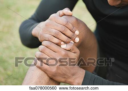 Man holding injured knee, cropped View Large Photo Image Stock Image - Man holding injured knee, cropped. Fotosearch
