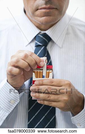 Man removing rolled euro from cigarette pack View Large Photo Image Stock Photo - Man removing rolled euro from cigarette pack. Fotosearch