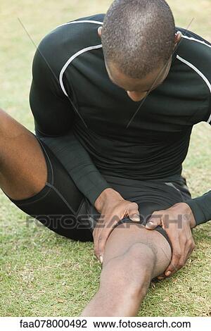 Stock Image - Man with cramp in thigh. Fotosearch