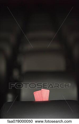 Stock Image - Movie tickets and empty seats in movie theater. Fotosearch