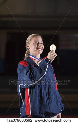 Smiling female athlete holding gold medal View Large Photo Image Stock Image - Smiling female athlete holding gold medal. Fotosearch