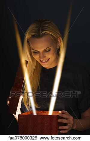 Woman illuminated by beams of light as she opens gift View Large Photo Image Stock Photograph - Woman illuminated by beams of light as she opens gift. Fotosearch