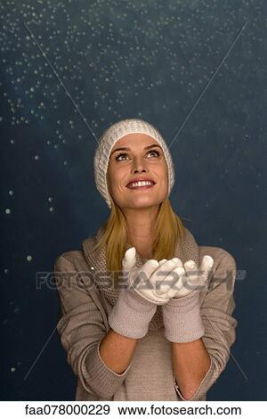 Stock Photo - Woman wearing knit hat and gloves in front of snowy background, portrait. Fotosearch