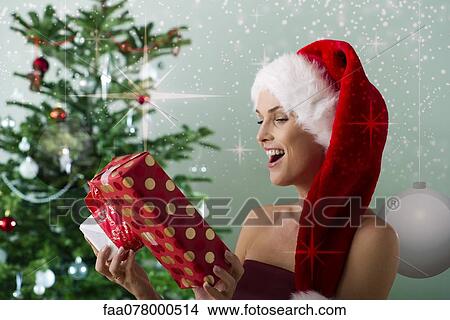 Woman wearing Santa hat, looking at Christmas gifts View Large Photo Image Picture - Woman wearing Santa hat, looking at Christmas gifts. Fotosearch