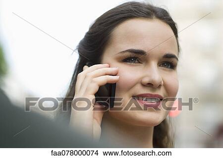 Picture - Yoiung woman using cell phone, smiling. Fotosearch