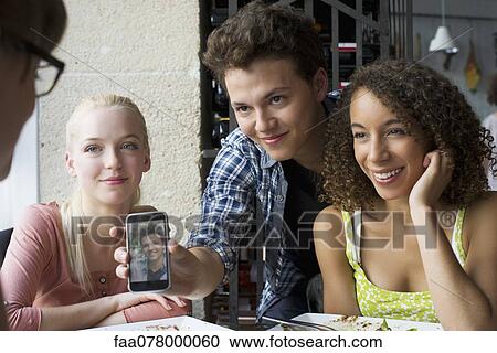 Young man showing friends photophone View Large Photo Image Stock Image - Young man showing friends photophone. Fotosearch