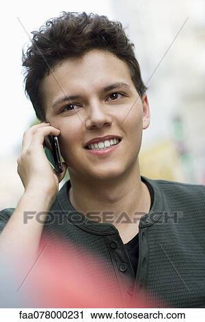 Stock Image - Young man using cell phone outdoors, portrait. Fotosearch