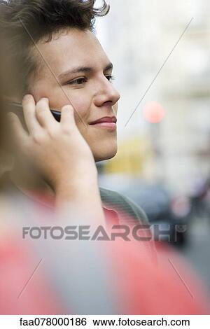 Stock Photograph - Young man using cell phone outdoors. Fotosearch