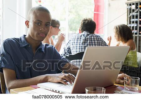 Young man using laptop computer in cafe View Large Photo Image Stock Photography - Young man using laptop computer in cafe. Fotosearch