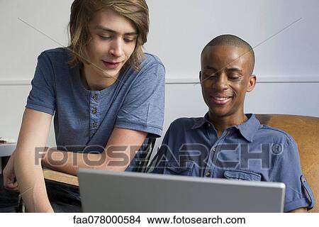 Young men using laptop computer together View Large Photo Image Picture - Young men using laptop computer together. Fotosearch