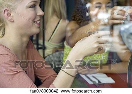 Young woman having drink in cafe with friends View Large Photo Image Stock Image - Young woman having drink in cafe with friends. Fotosearch