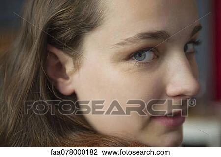 Stock Image - Young woman looking over shoulder, portrait. Fotosearch