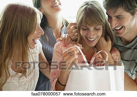 Stock Photo - Young woman opening gift from friends. Fotosearch