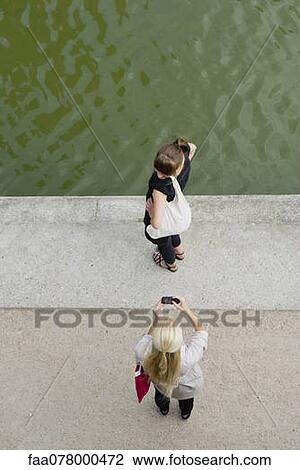 Young woman photographing friend with cell phone, elevated view View Large Photo Image Stock Image - Young woman photographing friend with cell phone, elevated view. Fotosearch