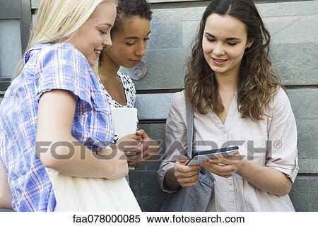 Stock Photography - Young woman showing digital tablet to friends. Fotosearch