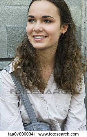 Stock Image - Young woman smiling, looking away, portrait. Fotosearch
