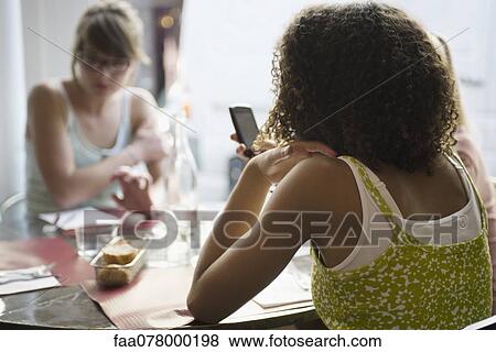 Young woman text messaging in cafe, rear view View Large Photo Image Stock Photo - Young woman text messaging in cafe, rear view. Fotosearch