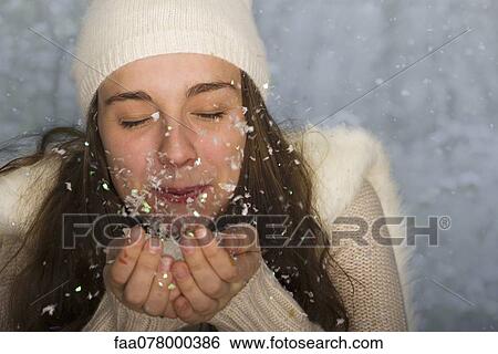 Young woman wearing winter clothing, blowing handful of confetti View Large Photo Image Stock Photograph - Young woman wearing winter clothing, blowing handful of confetti. Fotosearch