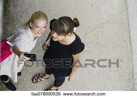 Stock Photo - Young women posing for cell phone picture. Fotosearch