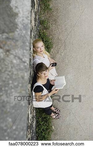Stock Image - Young women relaxing together outdoors, high angle view. Fotosearch
