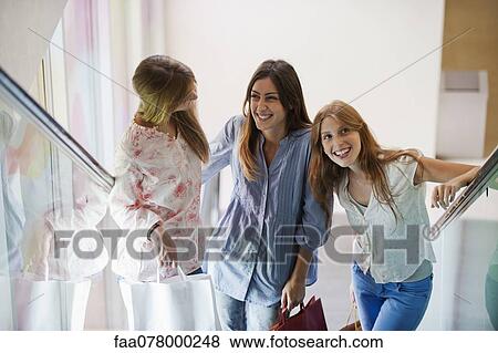 Young women standing on escalator, carrying shopping bags View Large Photo Image Stock Photo - Young women standing on escalator, carrying shopping bags. Fotosearch