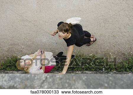 Stock Image - Young women standing together, looking up attentively. Fotosearch