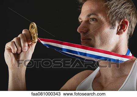 Stock Image - Athlete holding gold medal. Fotosearch