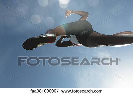 Stock Photo - Athlete in midair, low angle view. Fotosearch