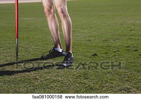 Athlete standing by pole, low section View Large Photo Image Stock Photo - Athlete standing by pole, low section. Fotosearch