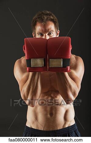 Barechested boxer holding up gloves in front of face in defensive position View Large Photo Image Stock Image - Barechested boxer holding up gloves in front of face in defensive position. Fotosearch