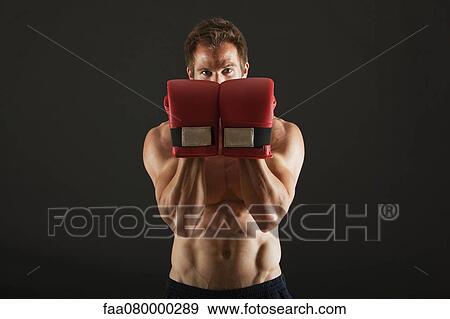 Stock Photo - Barechested boxer holding up gloves in front of face in defensive position. Fotosearch
