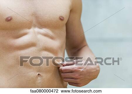 Stock Image - Barechested man pinching waist, mid section. Fotosearch