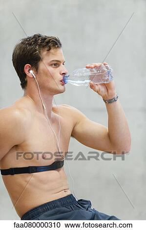 Stock Image - Barechested young man drinking bottled water. Fotosearch