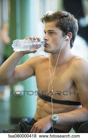 Stock Photo - Barechested young man drinking bottled water. Fotosearch