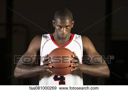 Stock Photo - Basketball player holding basketball, portrait. Fotosearch