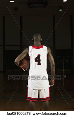 Stock Photo - Basketball player holding basketball, rear view. Fotosearch