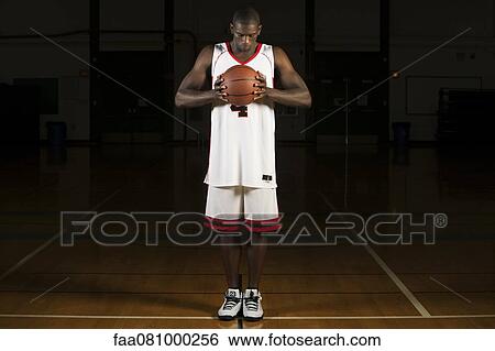 Stock Photograph - Basketball player holding basketball, portrait. Fotosearch