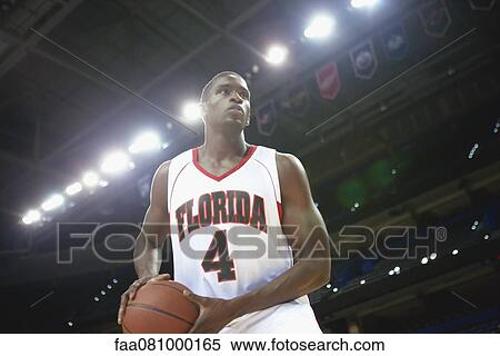 Stock Photography - Basketball player holding basketball low angle view. Fotosearch