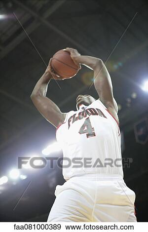 Stock Photo - Basketball player jumping with basketball, low angle view. Fotosearch