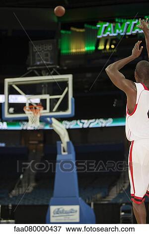 Stock Photo - Basketball player shooting basketball, rear view. Fotosearch