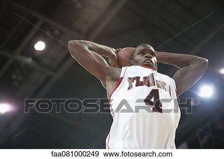 Stock Photo - Basketball player shooting basketball, low angle view. Fotosearch