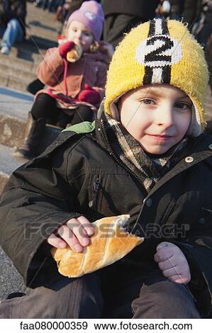 Boy eating pastry outdoors, portrait View Large Photo Image Stock Photo - Boy eating pastry outdoors, portrait. Fotosearch