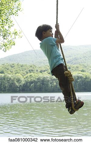 Boy hanging from rope over river View Large Photo Image Stock Image - Boy hanging from rope over river. Fotosearch